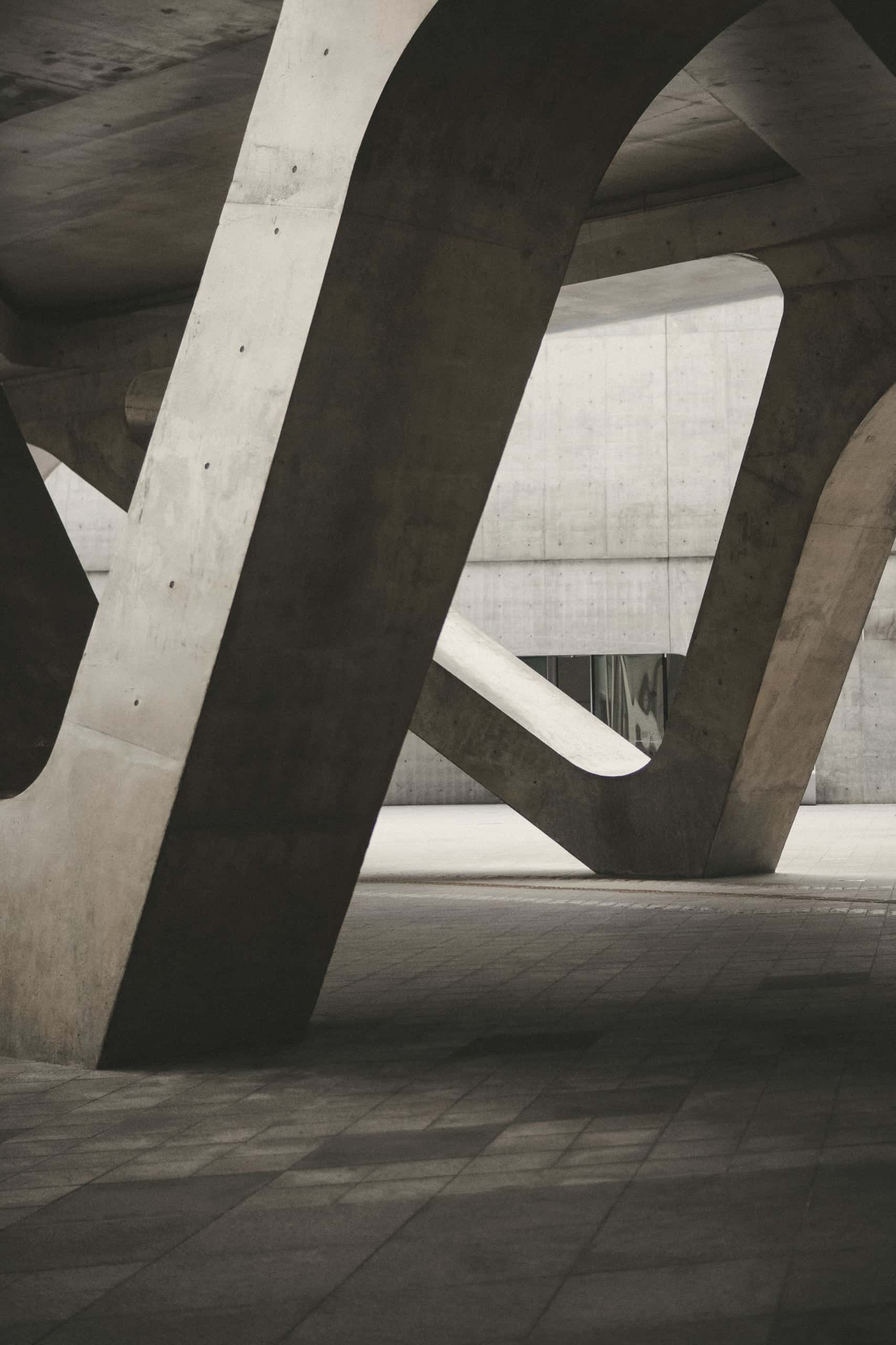 Angled concrete legs supporting a roof above a shaded ground plane.