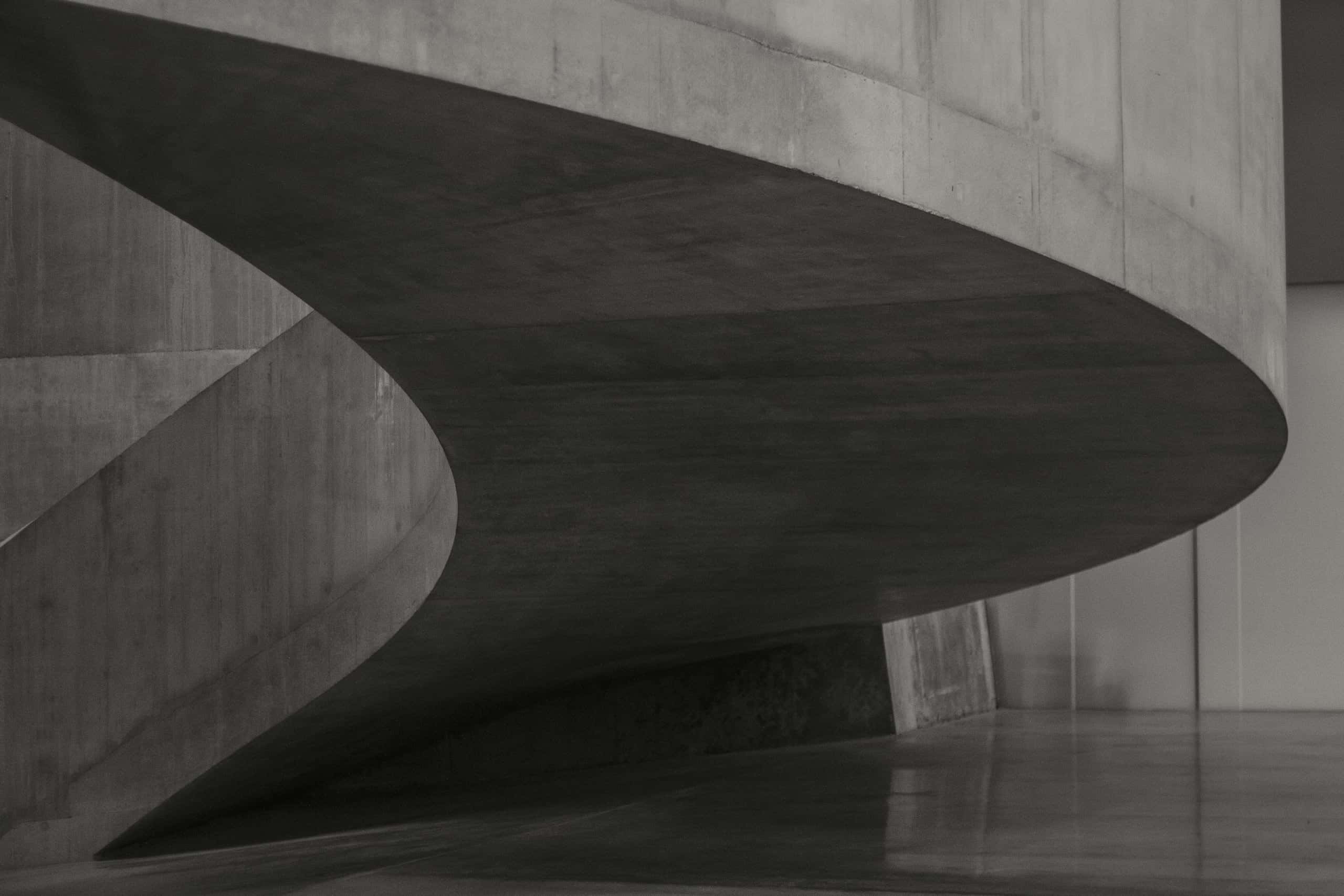 A curved concrete ramp sweeping around a dim, double-height interior.