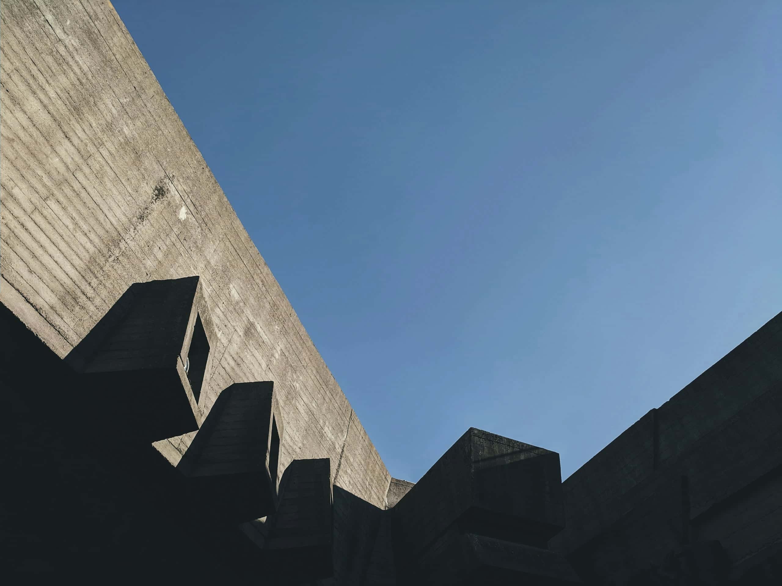 A sawtooth concrete roofline cutting across a deep blue sky.