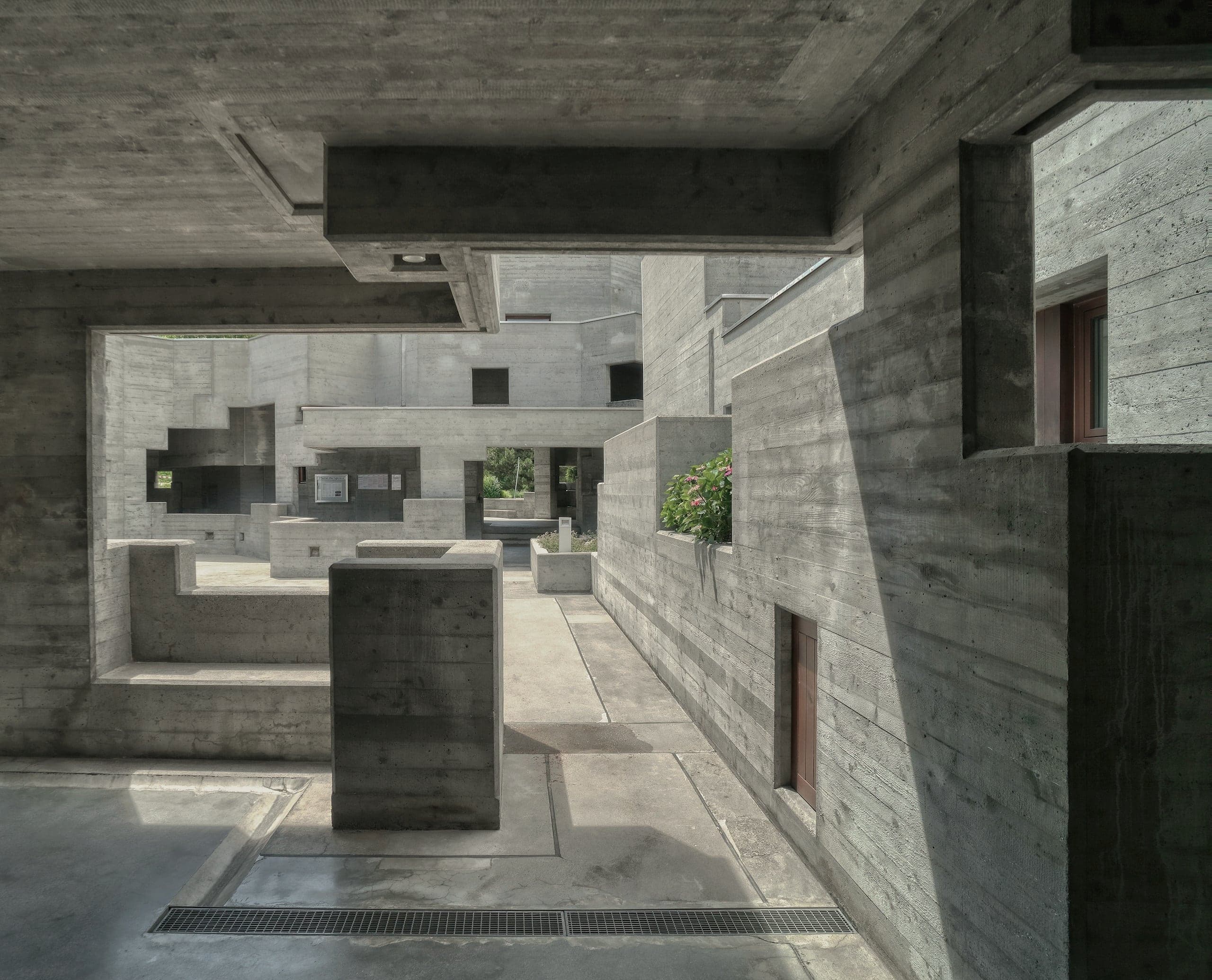 A concrete courtyard of stacked volumes, niches and openings.