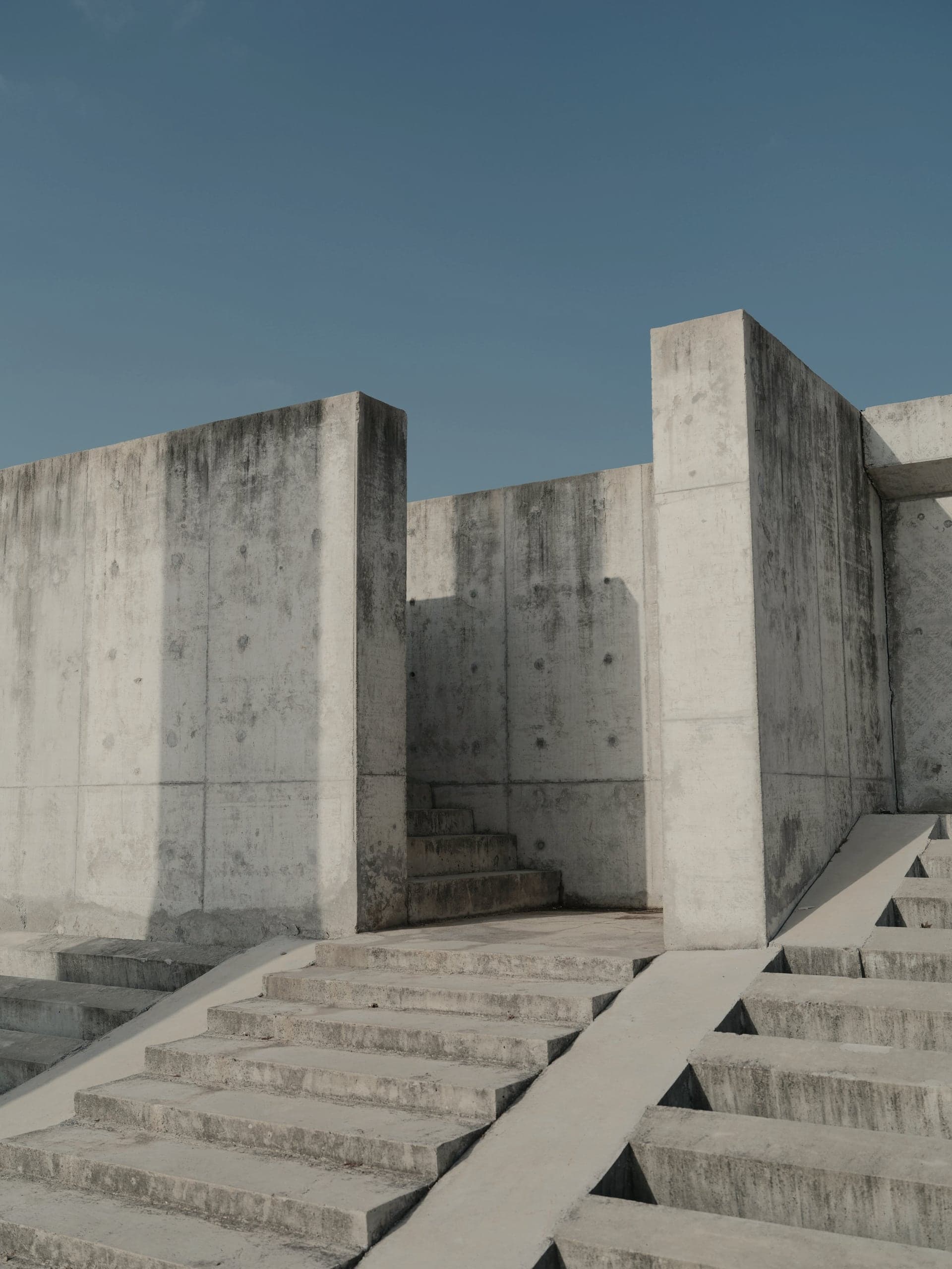 Concrete walls and stairs stepping up against a clear blue sky.