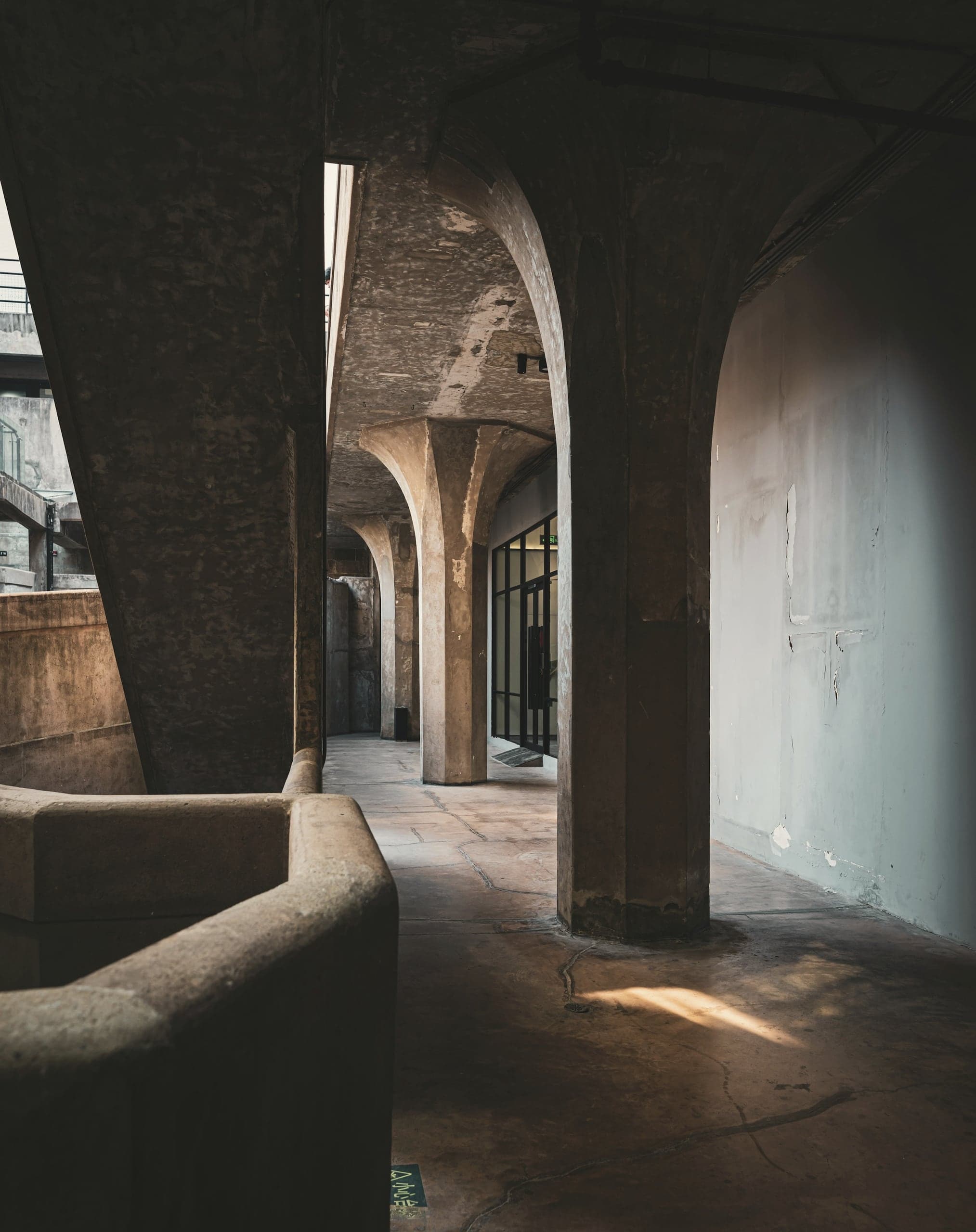 A shadowed arcade of heavy piers, a pool of sunlight on the floor.