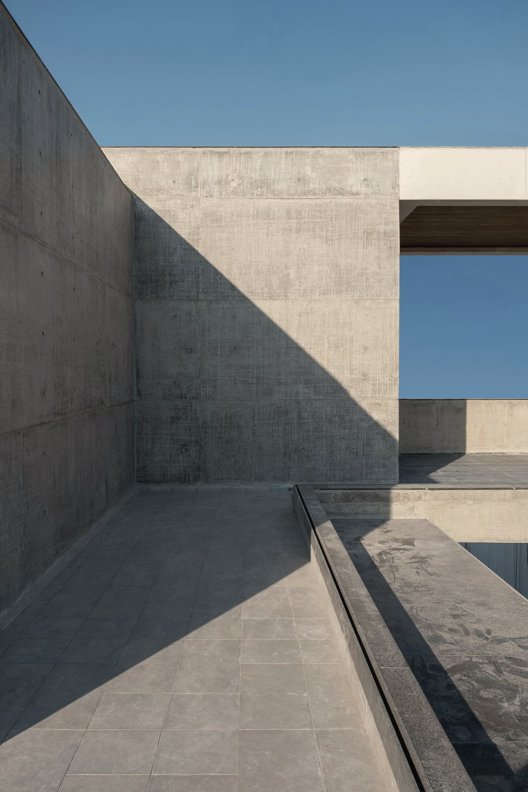 A walled concrete court open to the sky, a single slot framing the blue beyond.