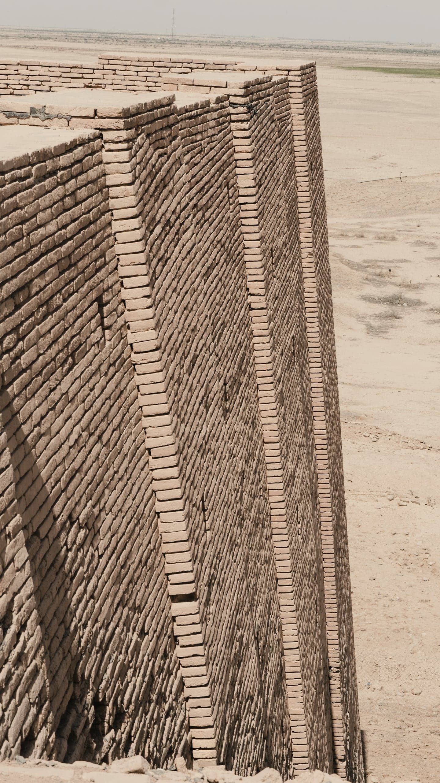 A layered earth wall standing on a flat desert plain.