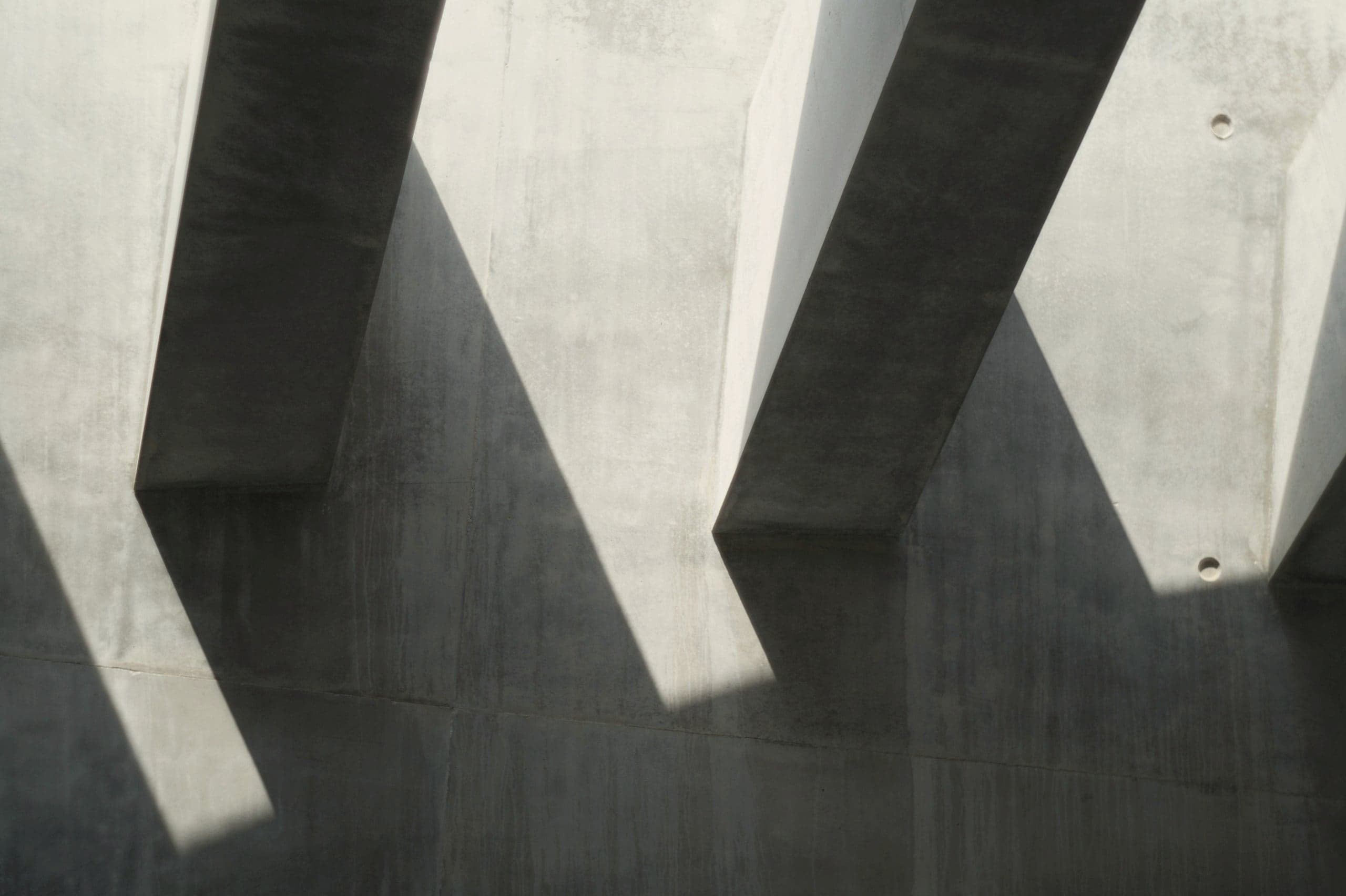 Deep concrete fins casting diagonal shadows across a pale wall.