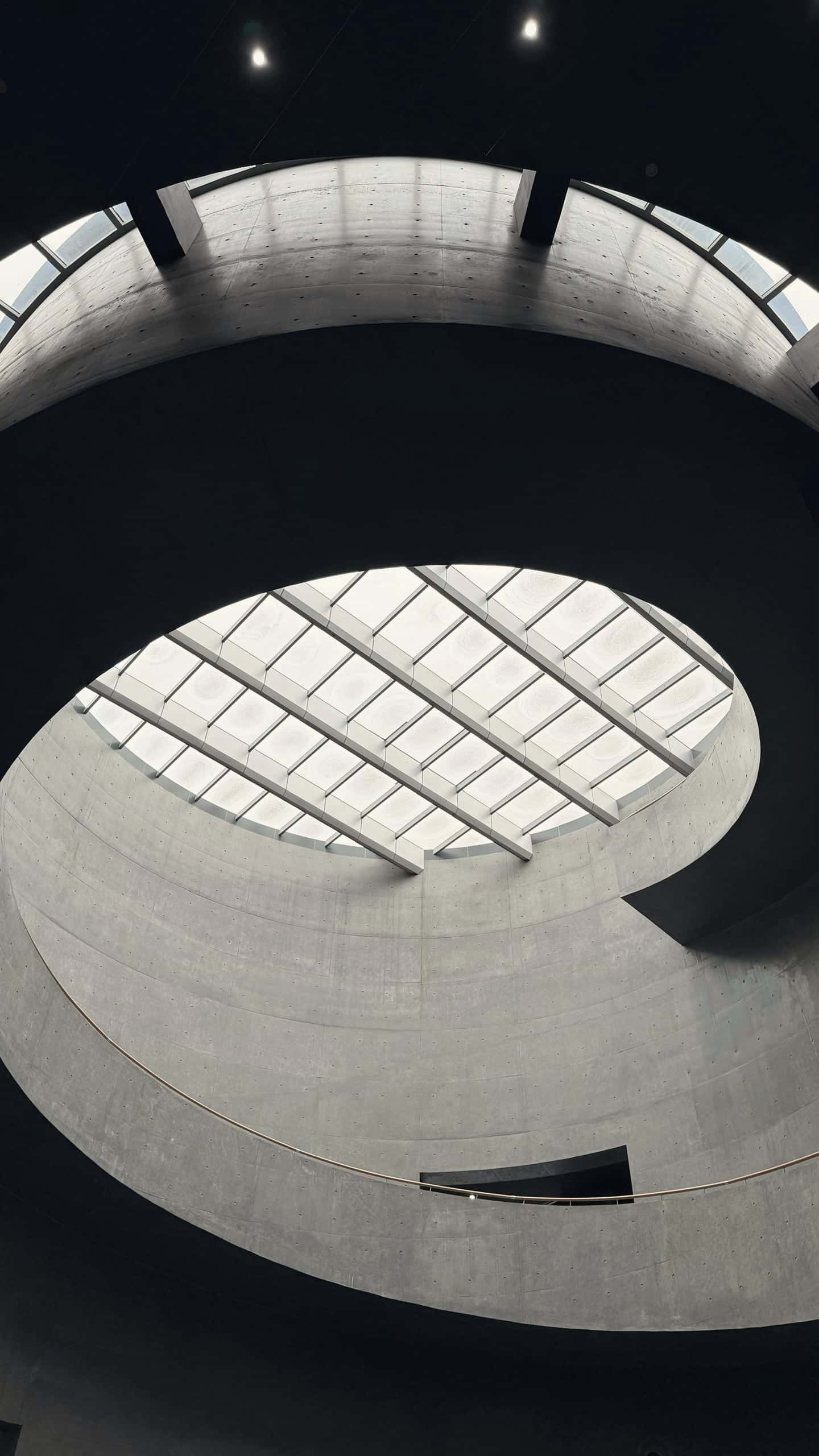 A spiralling concrete interior looking up to an oval rooflight.