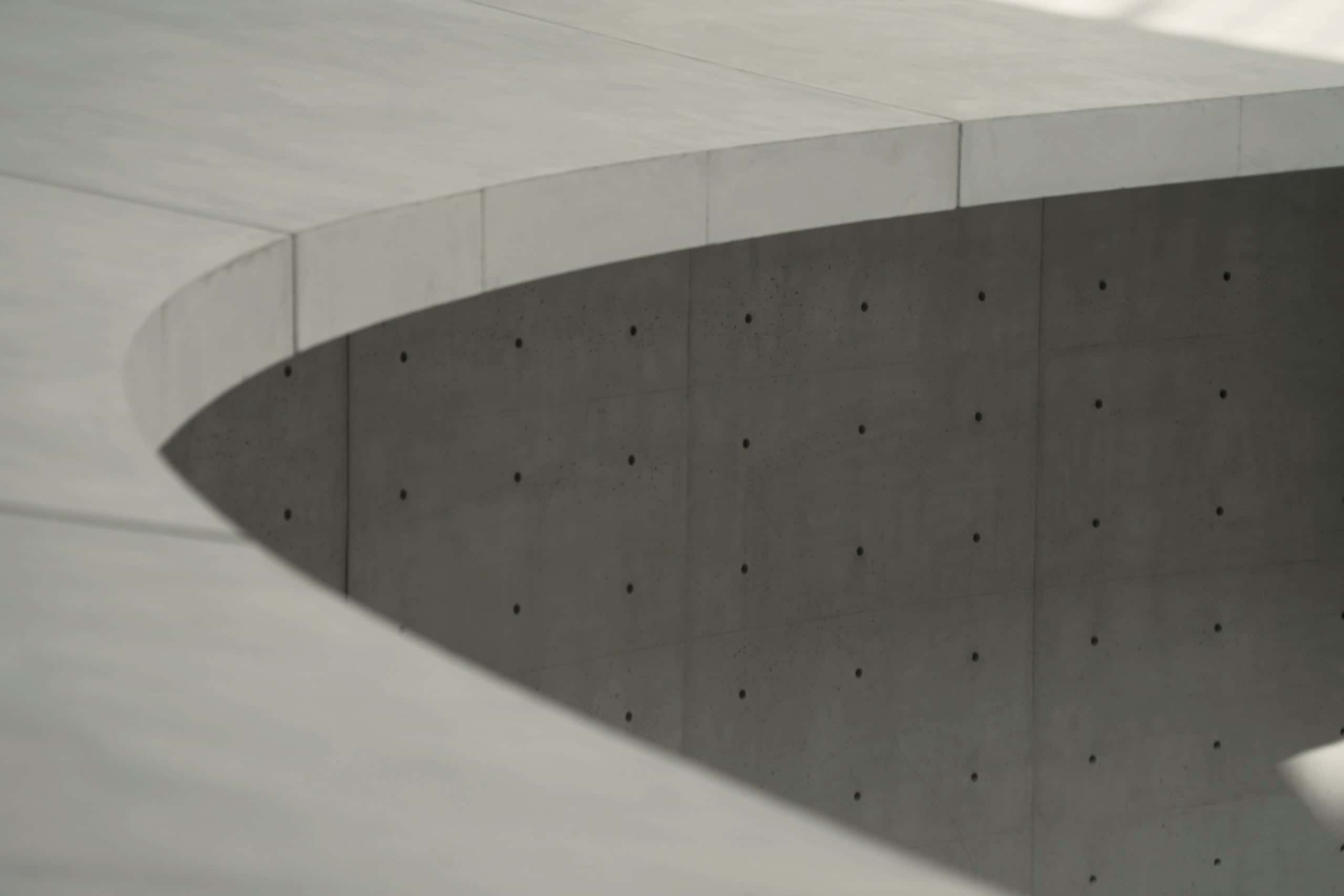 A curved concrete soffit meeting a wall of evenly spaced tie holes.
